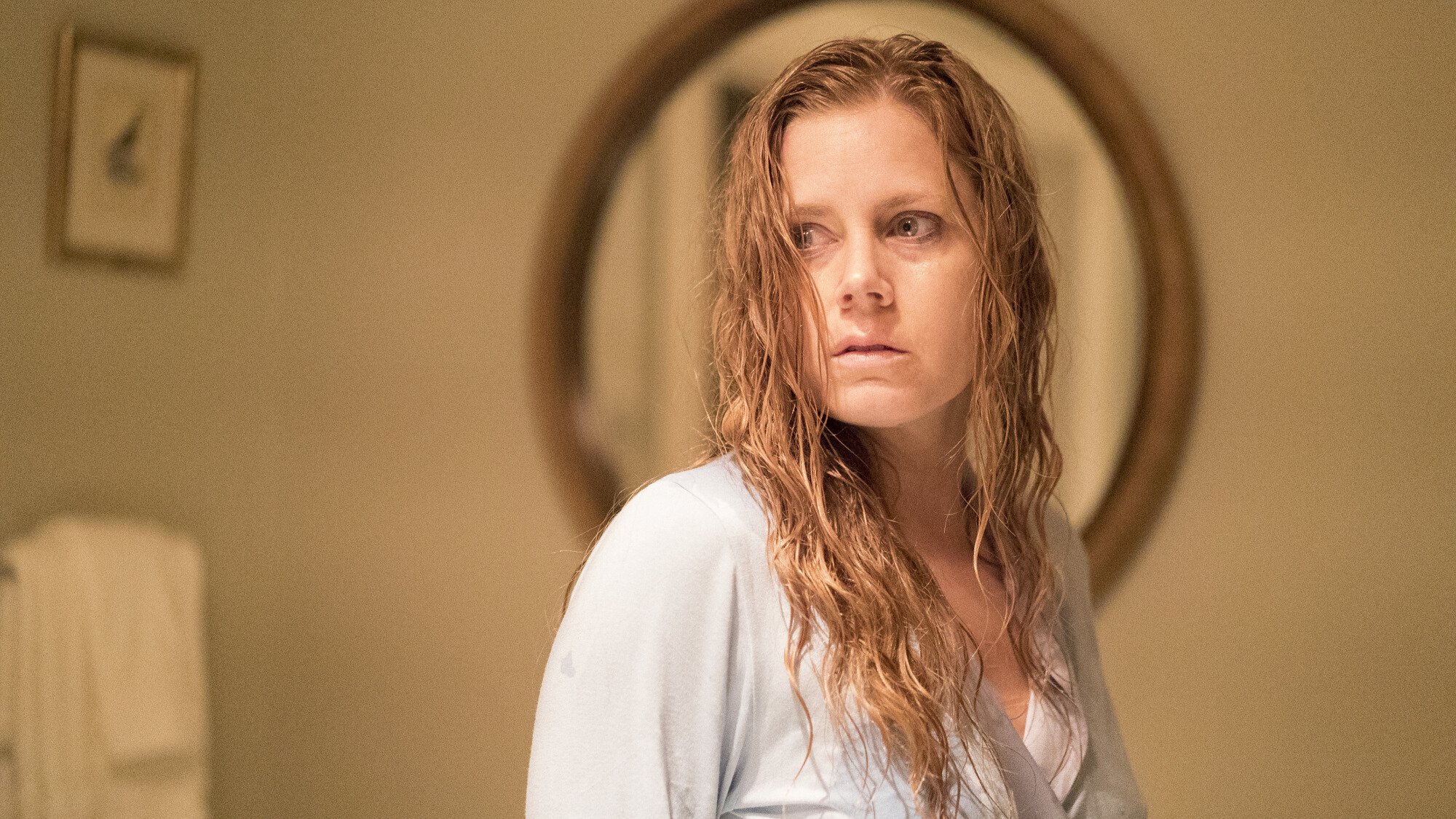 A woman looks terrified while standing in her bathroom. 