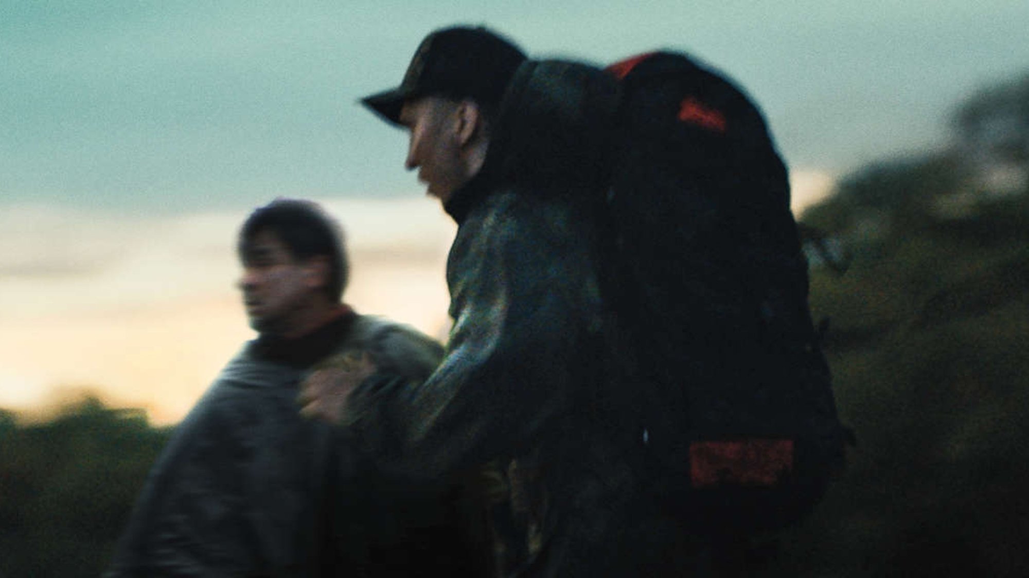 Two people wearing backpacks run at dusk in the TV seies "Escape at Dannemora"