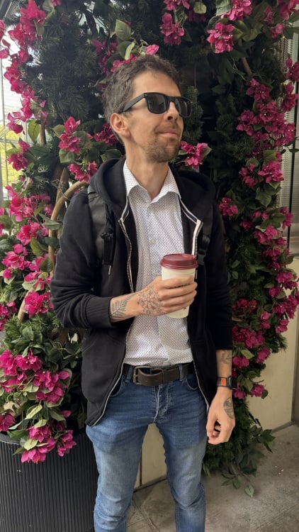 Man standing in front of a bunch of pink roses