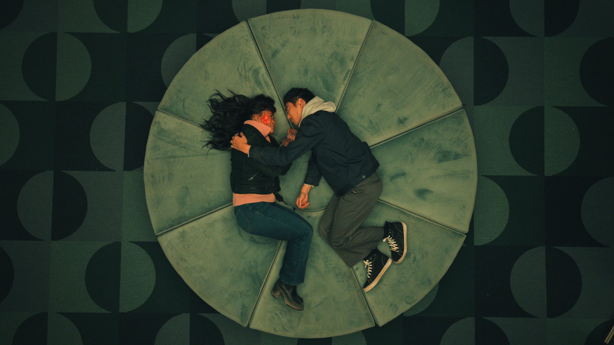 Victoria Sawal and Justin H. Min lie on a circular couch, seen from above in "The Umbrella Academy."