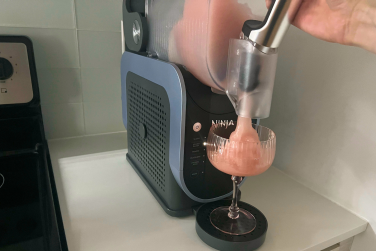 Ninja Slushi machine dispensing pink frosé into glass sitting underneath