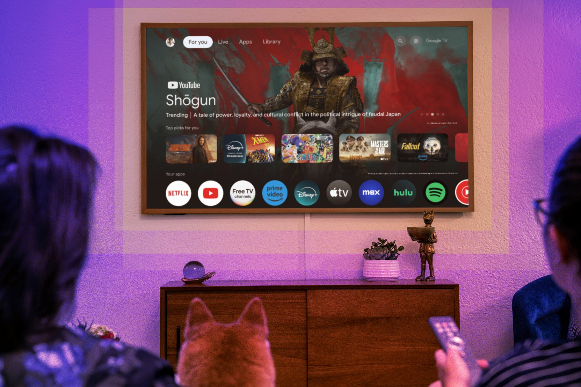 People and a dog on the couch picking something to watch on the Hisense CanvasTV Google TV homescreen