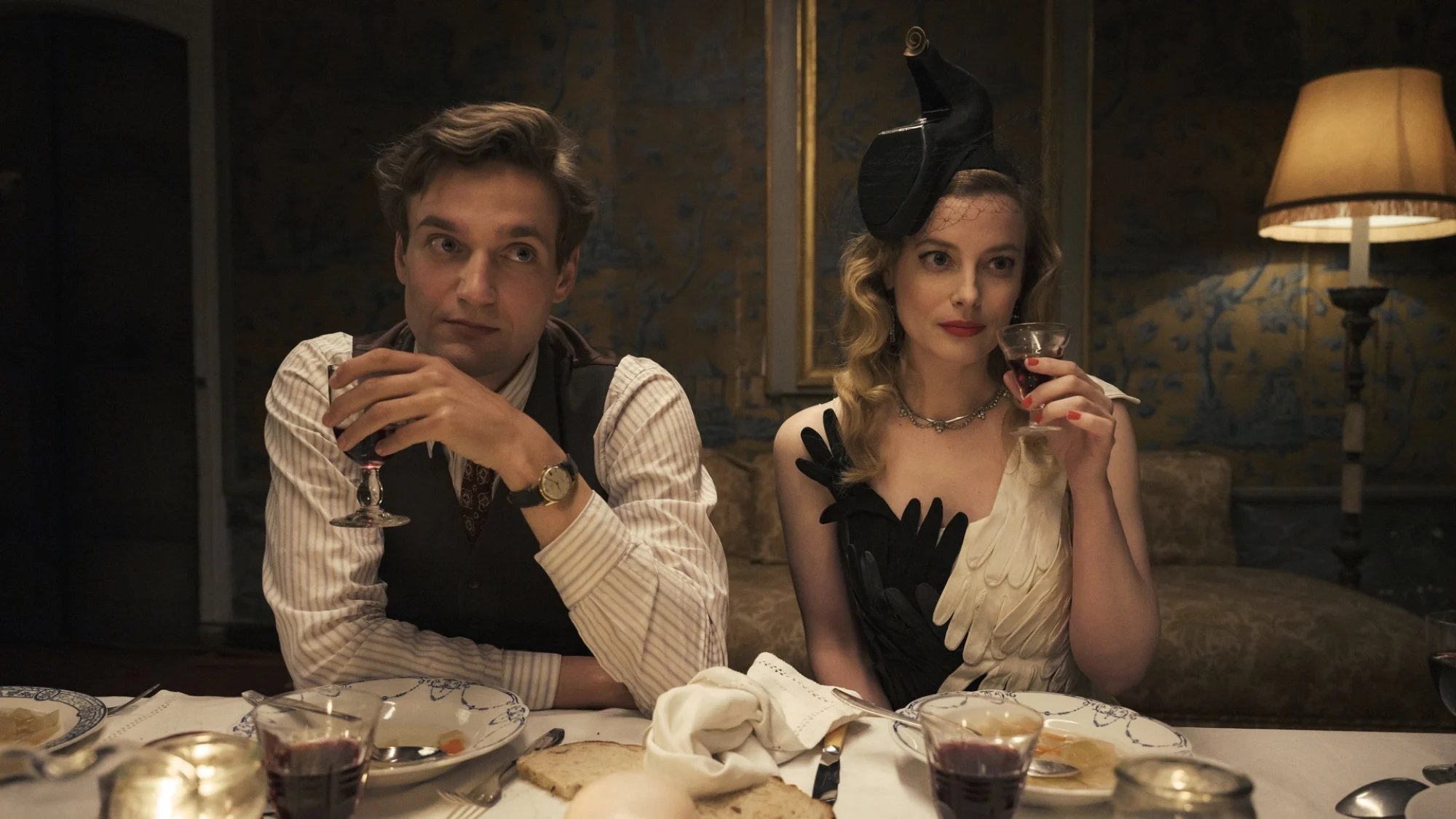 A 1940s couple drink wine during dinner. 