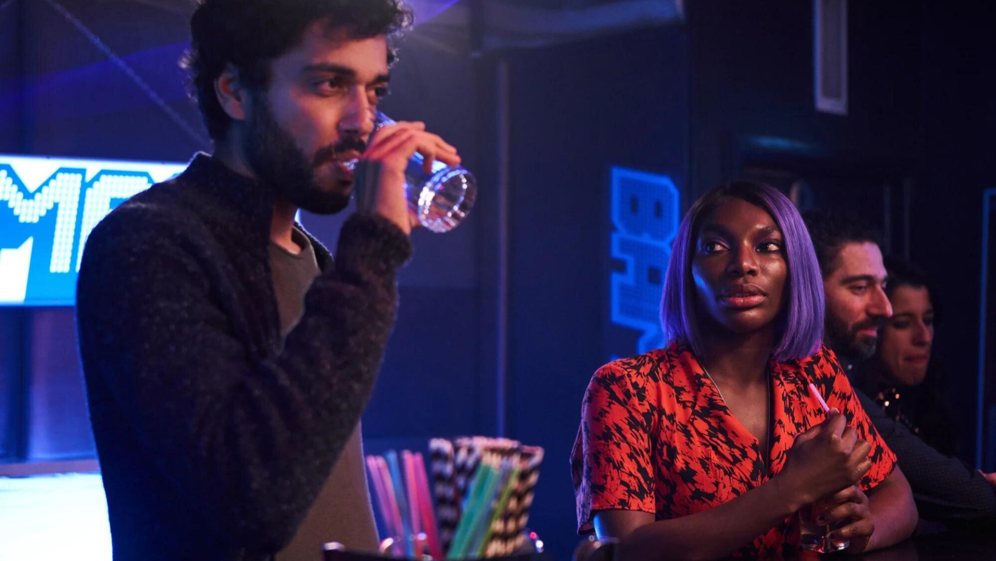 A man and a woman drink at a bar in a nightclub. 