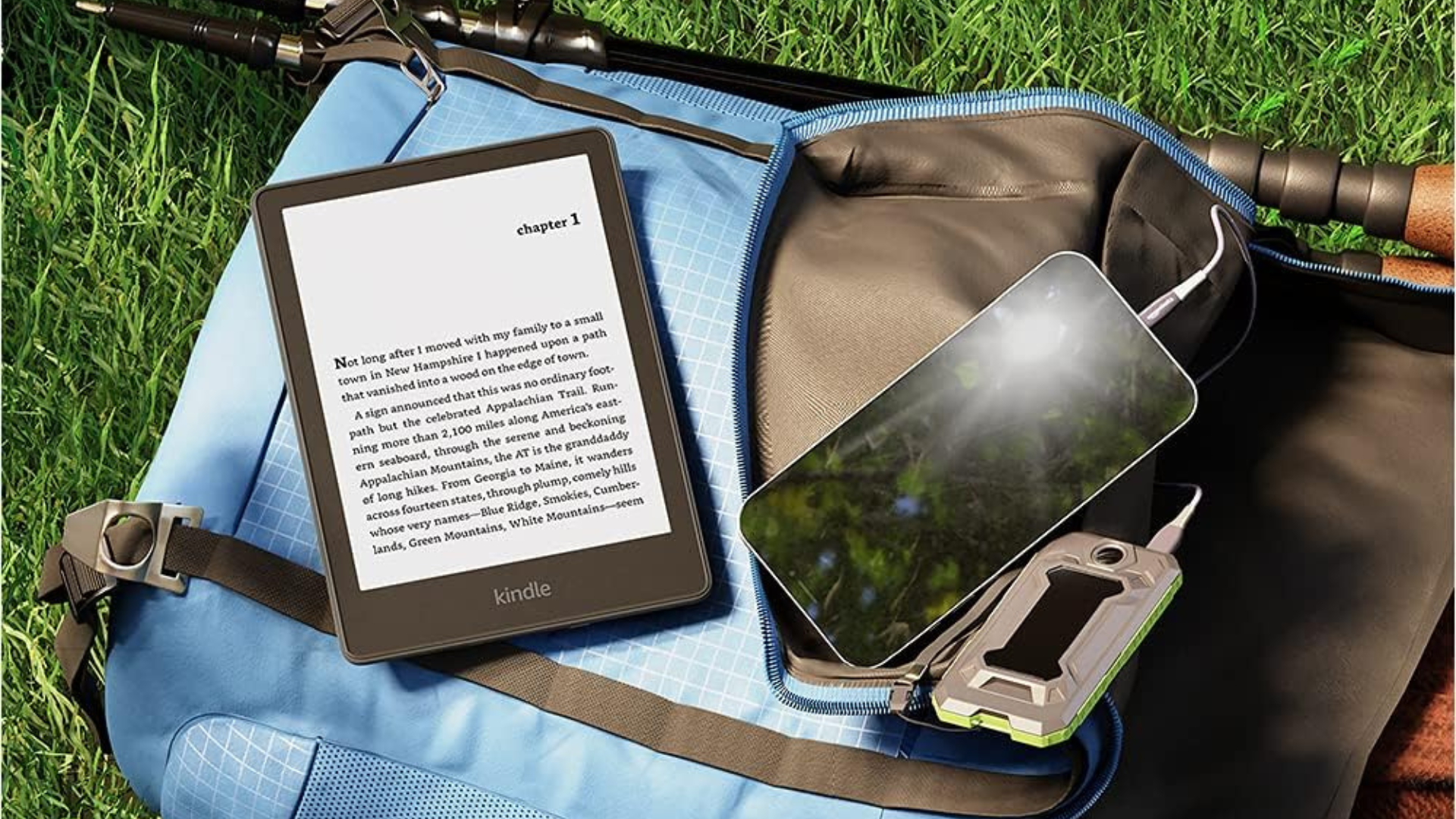 A Kindle laying on a backpack outside.