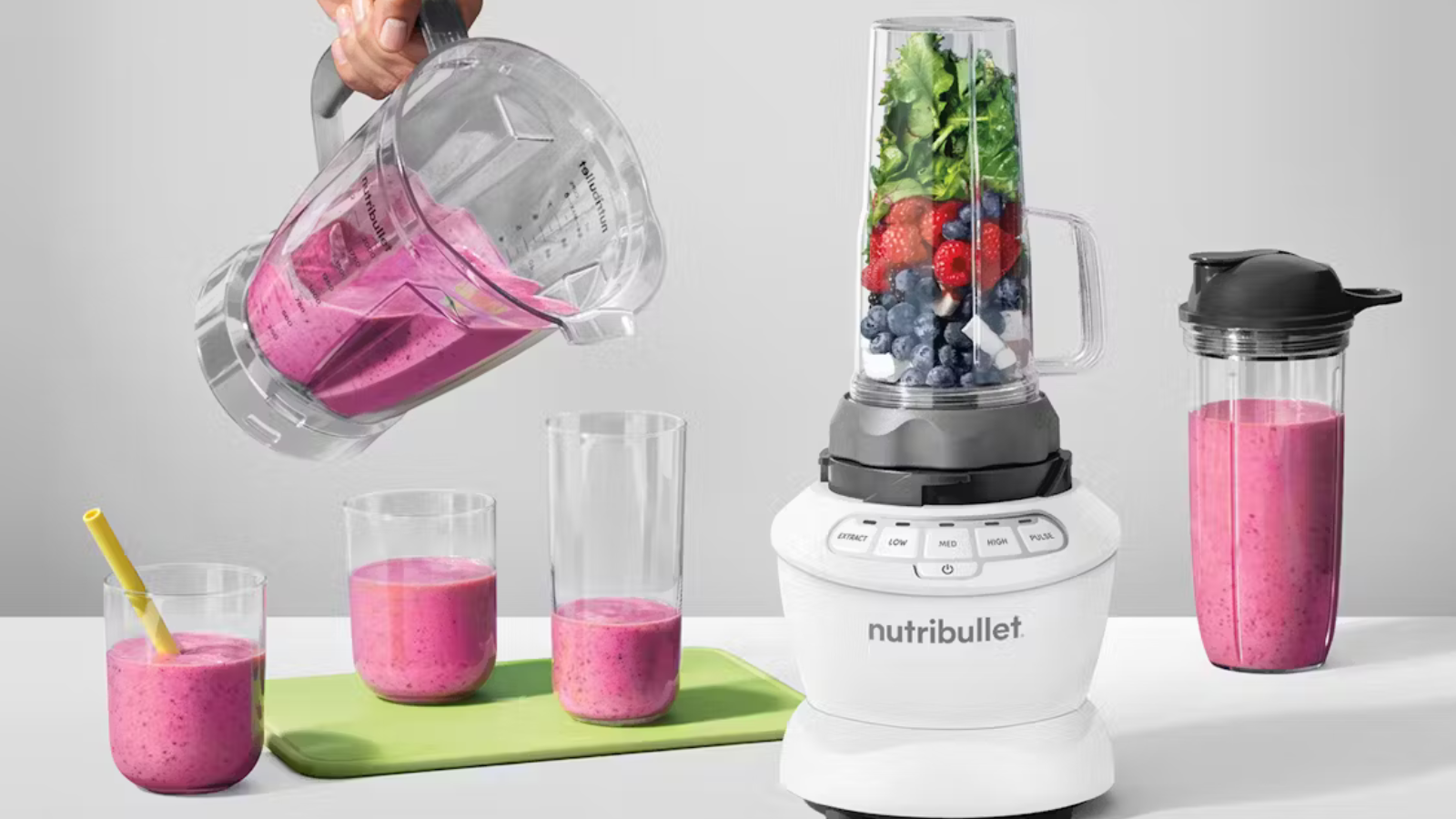 nutribullet blender filled with fruits surrounded by cups full of smoothie