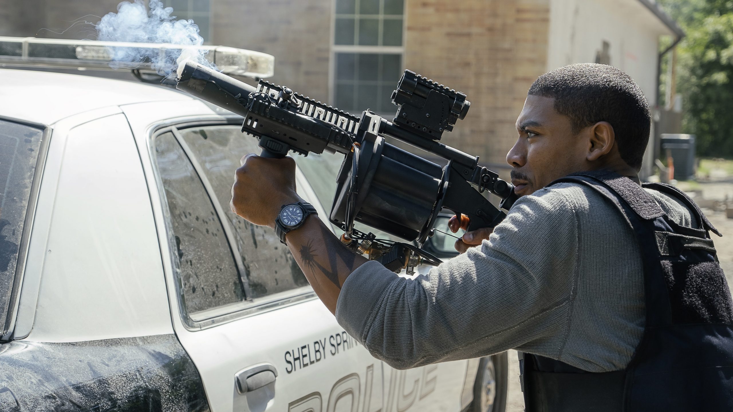 Terry Richmond fires a gun over a cop car.