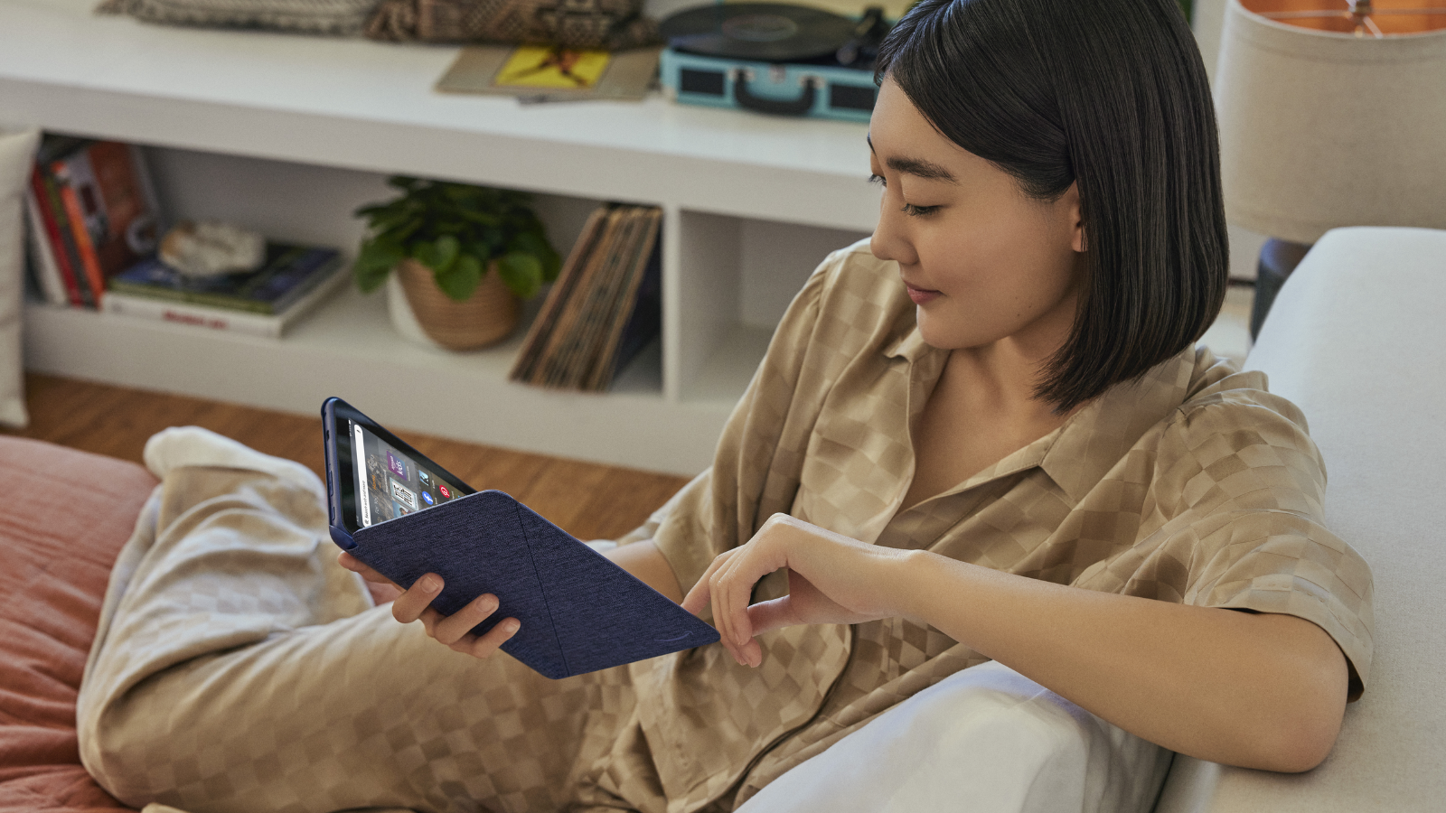 a woman sitting on a couch looking at an amazon fire hd 8 tablet in a blue case