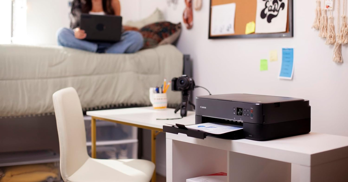 girl sitting on dorm room bed behind a printer 