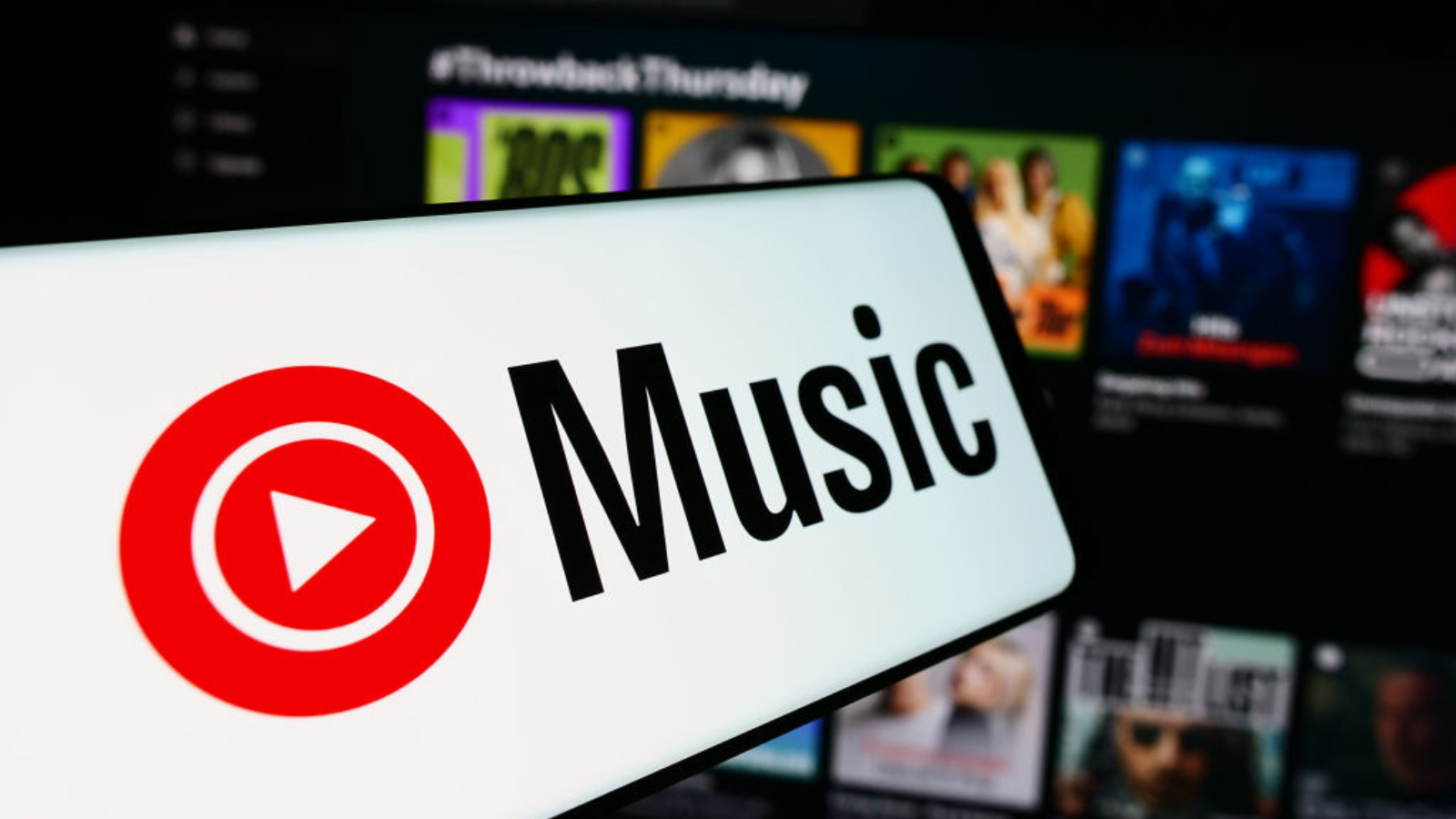 In this photo illustration, a mobile phone with the logo of American music streaming service YouTube Music is seen in front of business website. 