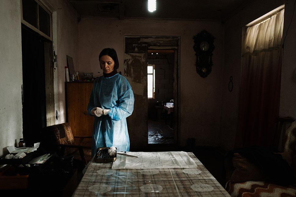 A woman in surgical dress stands alone in a room.