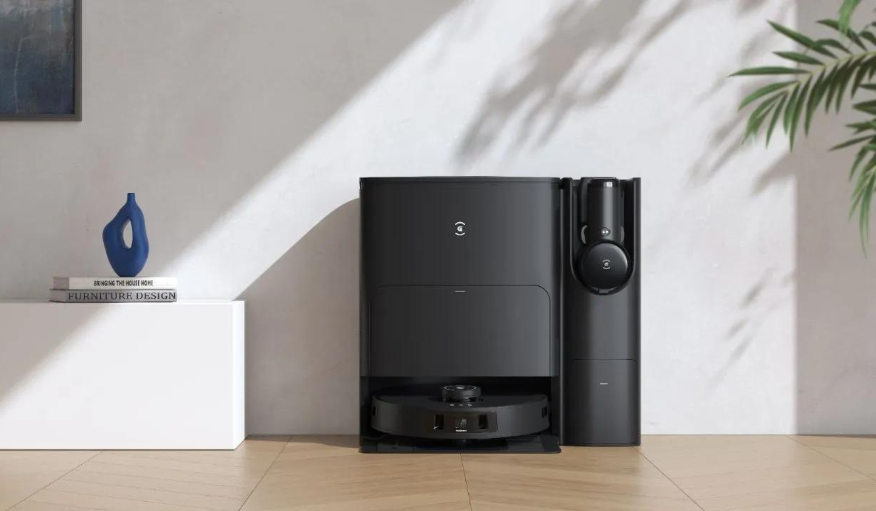 Ecovacs robot vacuum and self-emptying dock sitting against wall by TV stand