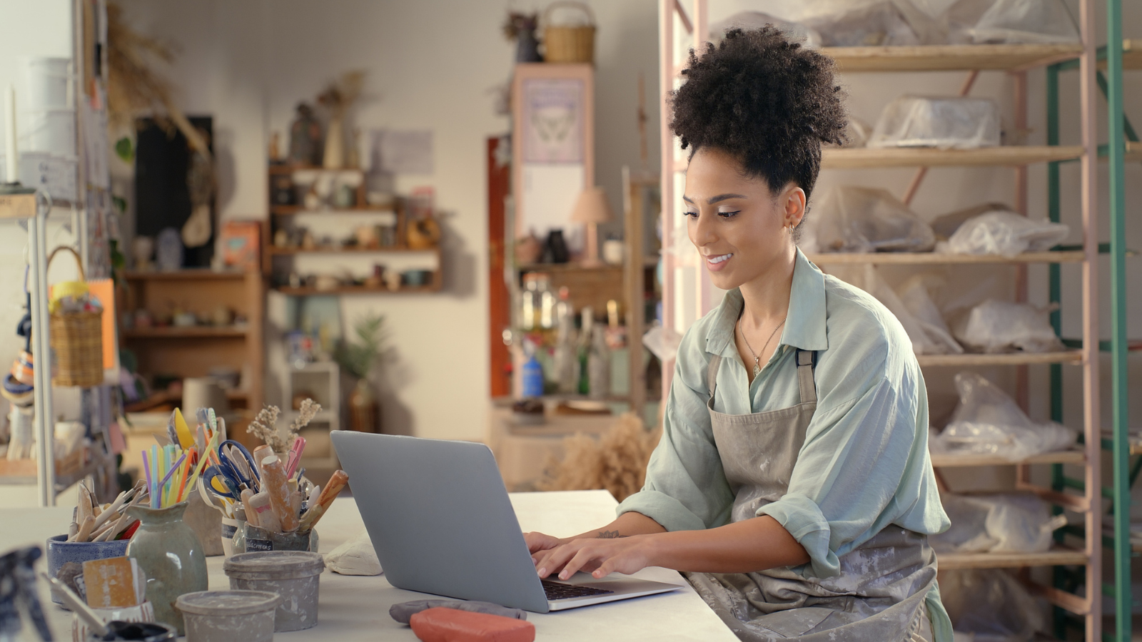 Laptop, pottery studio and woman typing ceramic sales website