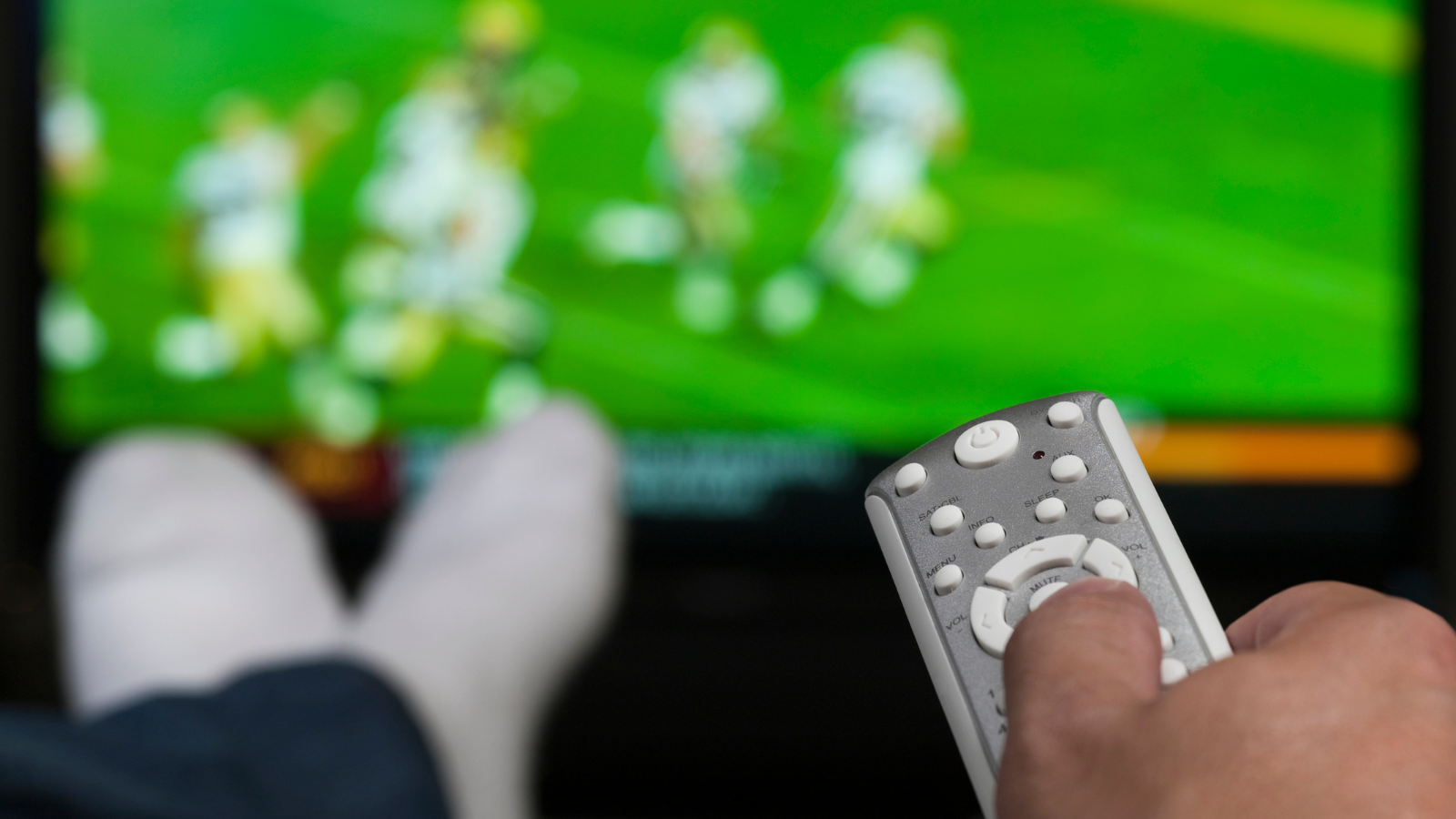 person lounging on couch watching football