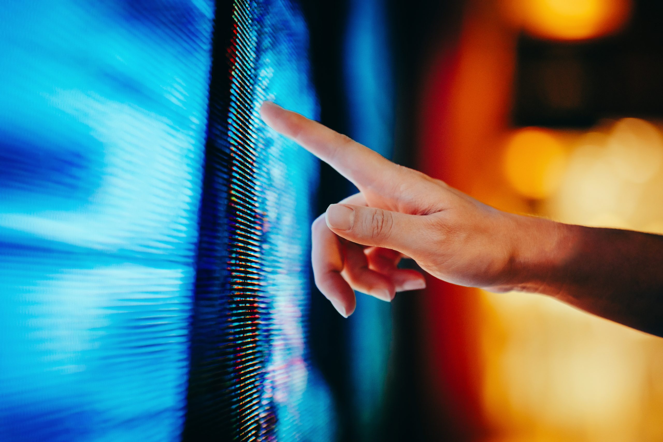 Close up of woman's hand touching illuminated and multi-coloured LED display screen