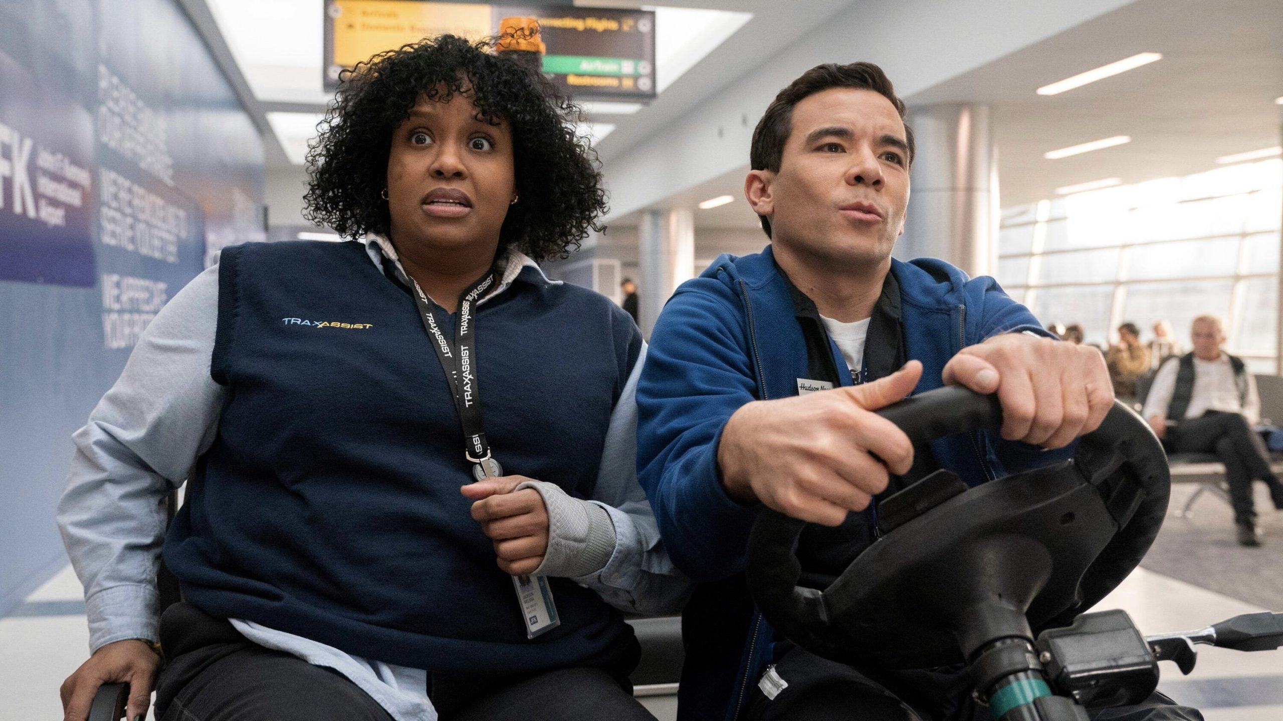 Mel and Rory race through JFK airport on a cart.