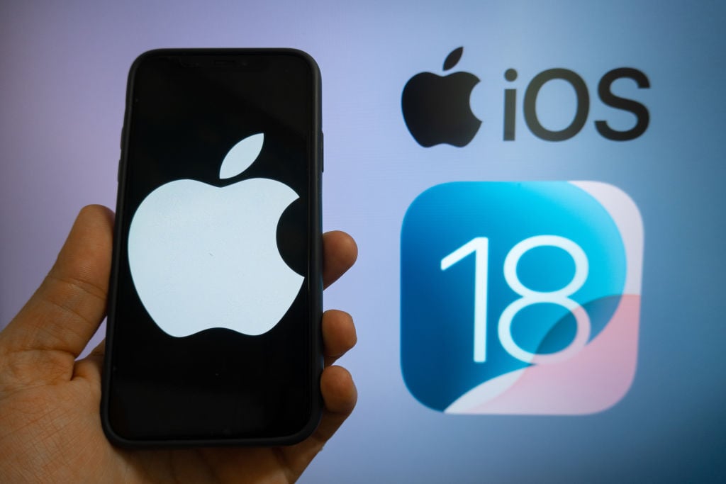 The Apple logo is seen with the iOS 18 operating system logo in the background on a mobile device