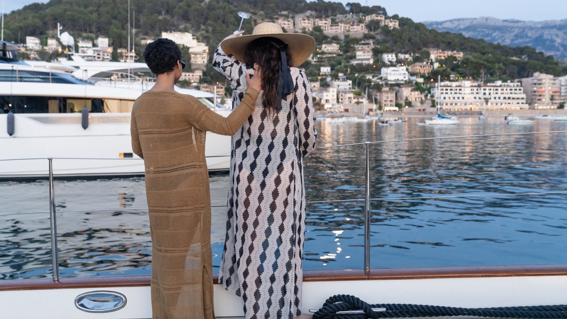 Harper and Yasmin pour champagne off the deck of a yacht.