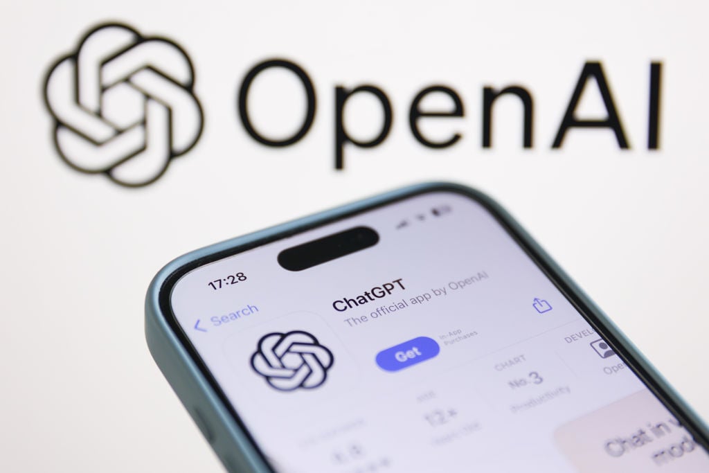 OpenAI logo displayed on a laptop screen and ChatGPT on AppStore displayed on a phone screen