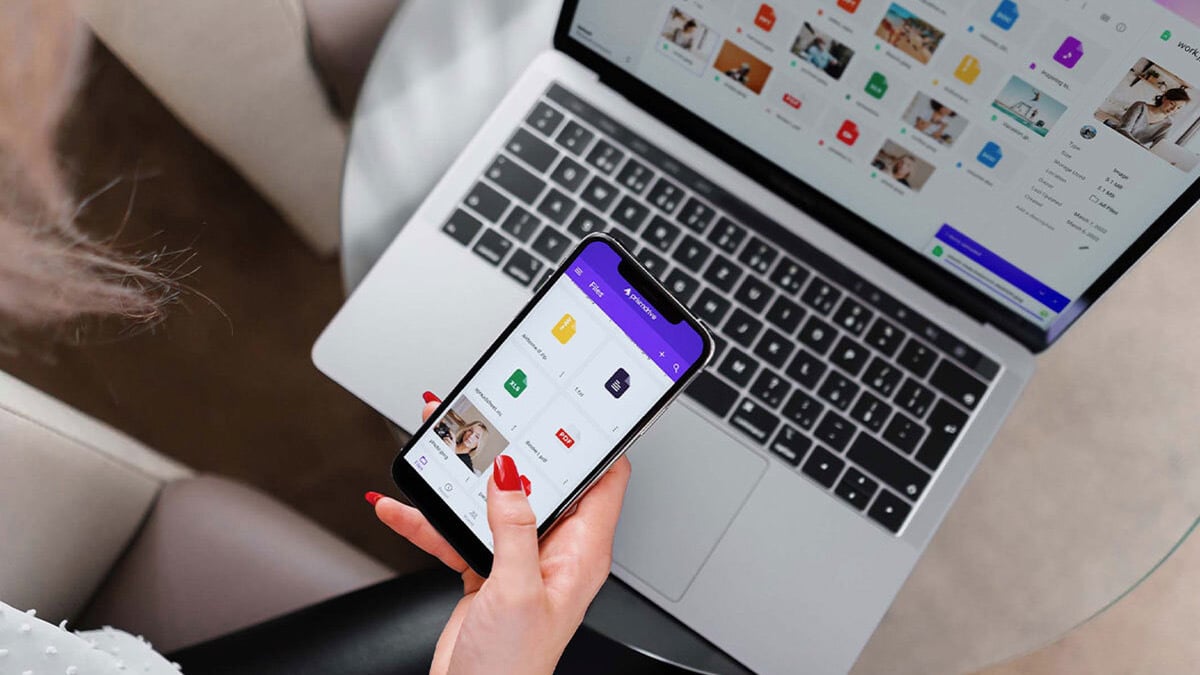 woman holding phone in front of laptop