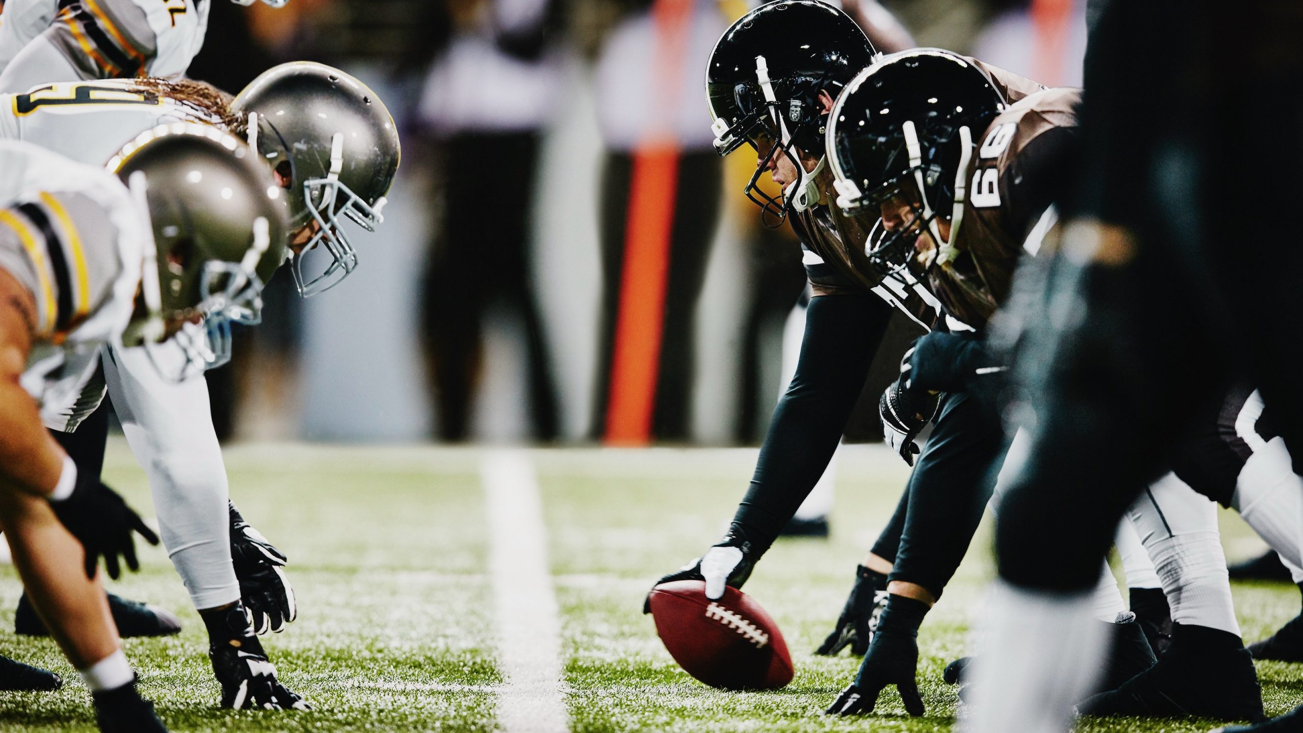 two football teams on the line of scrimmage preparing for snap