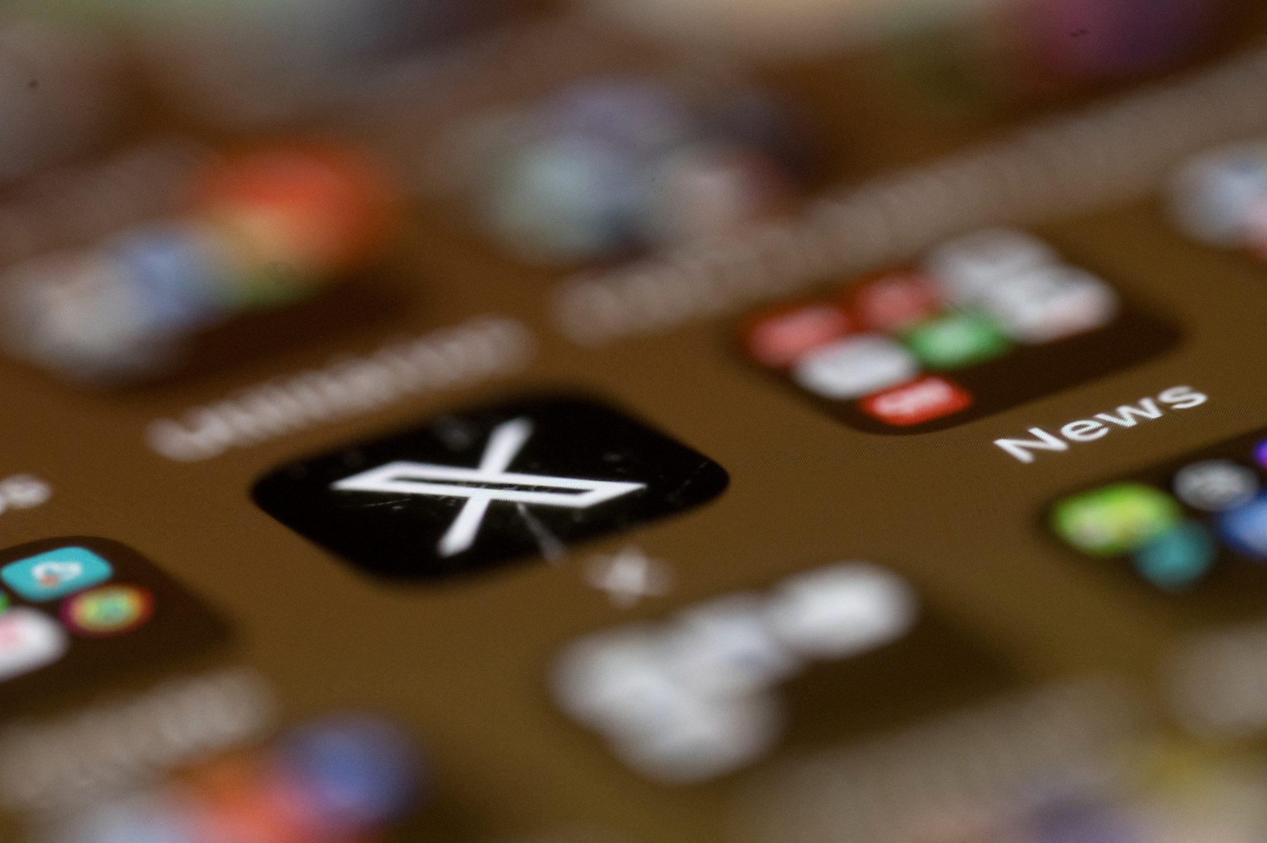 A blurry phone screen, with only the X app logo in focus. 