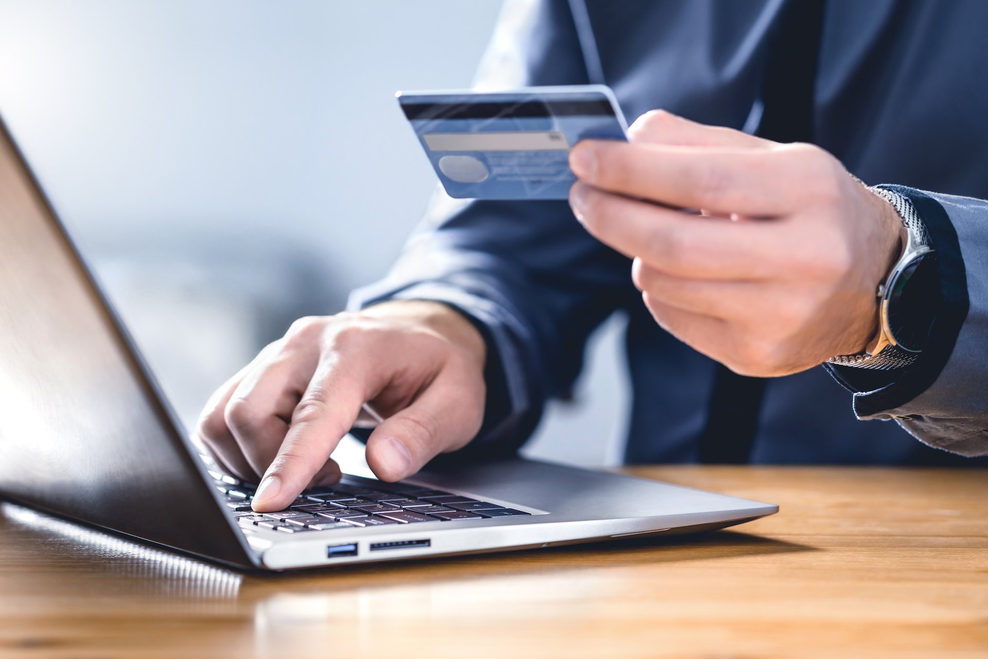 A man on a computer is using his credit card to purchase something.