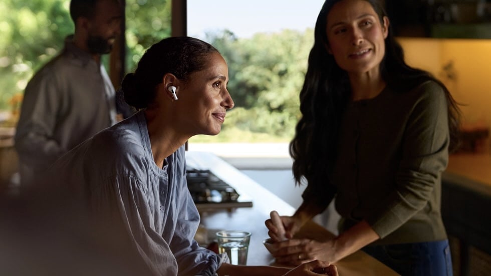 person wearing airpods leaning over counter talking to other people