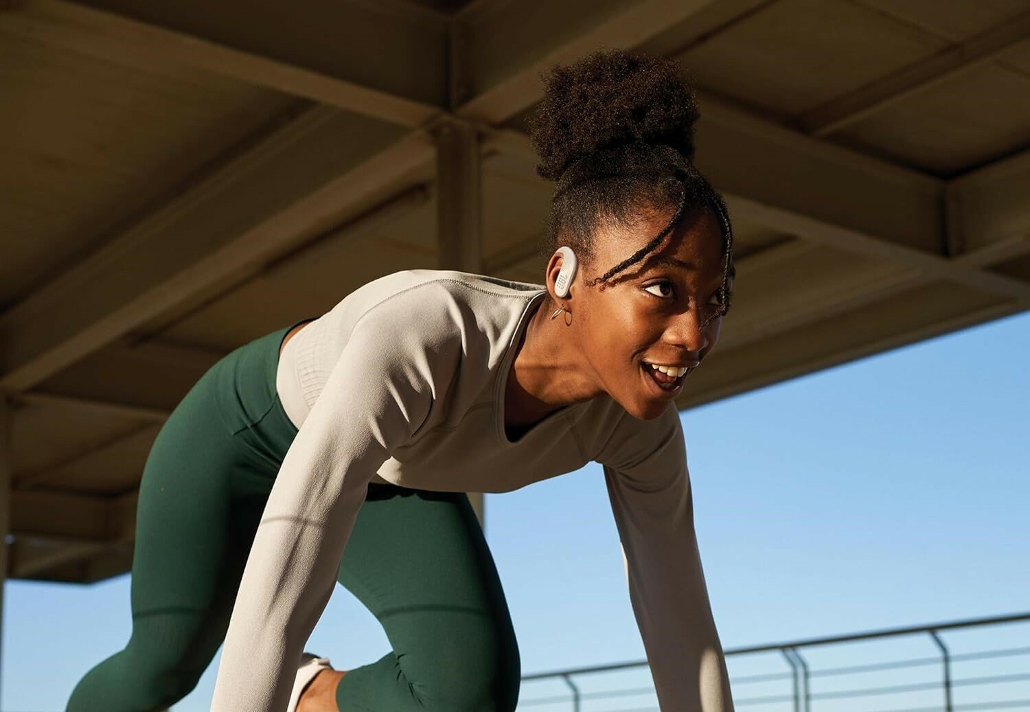 a female runner in the starting spring position wears the jbl endurance peak 3 headphones