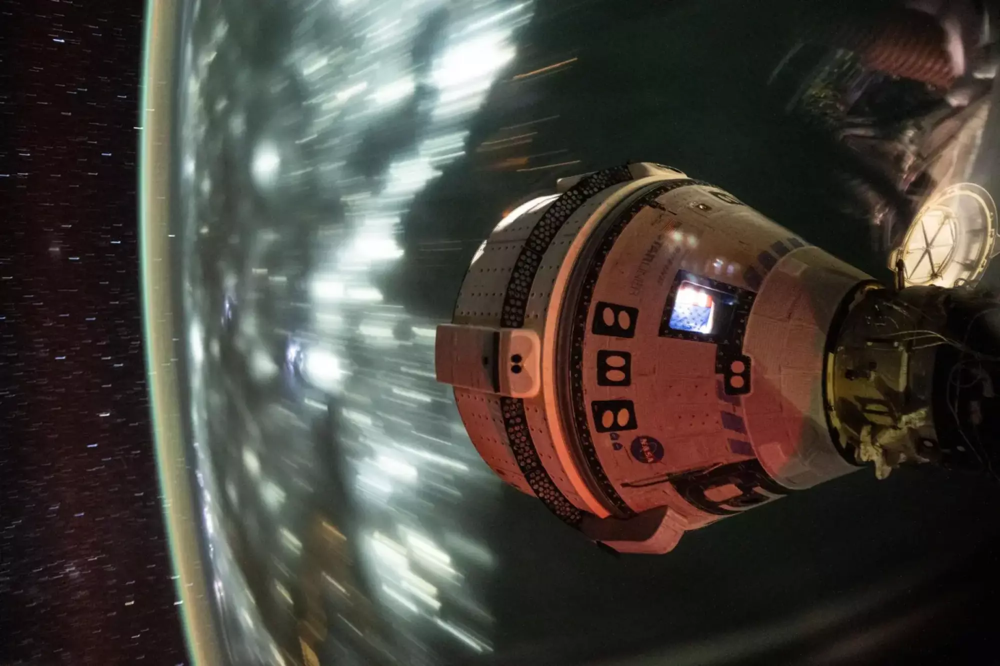 Starliner flying in space while docked at International Space Station