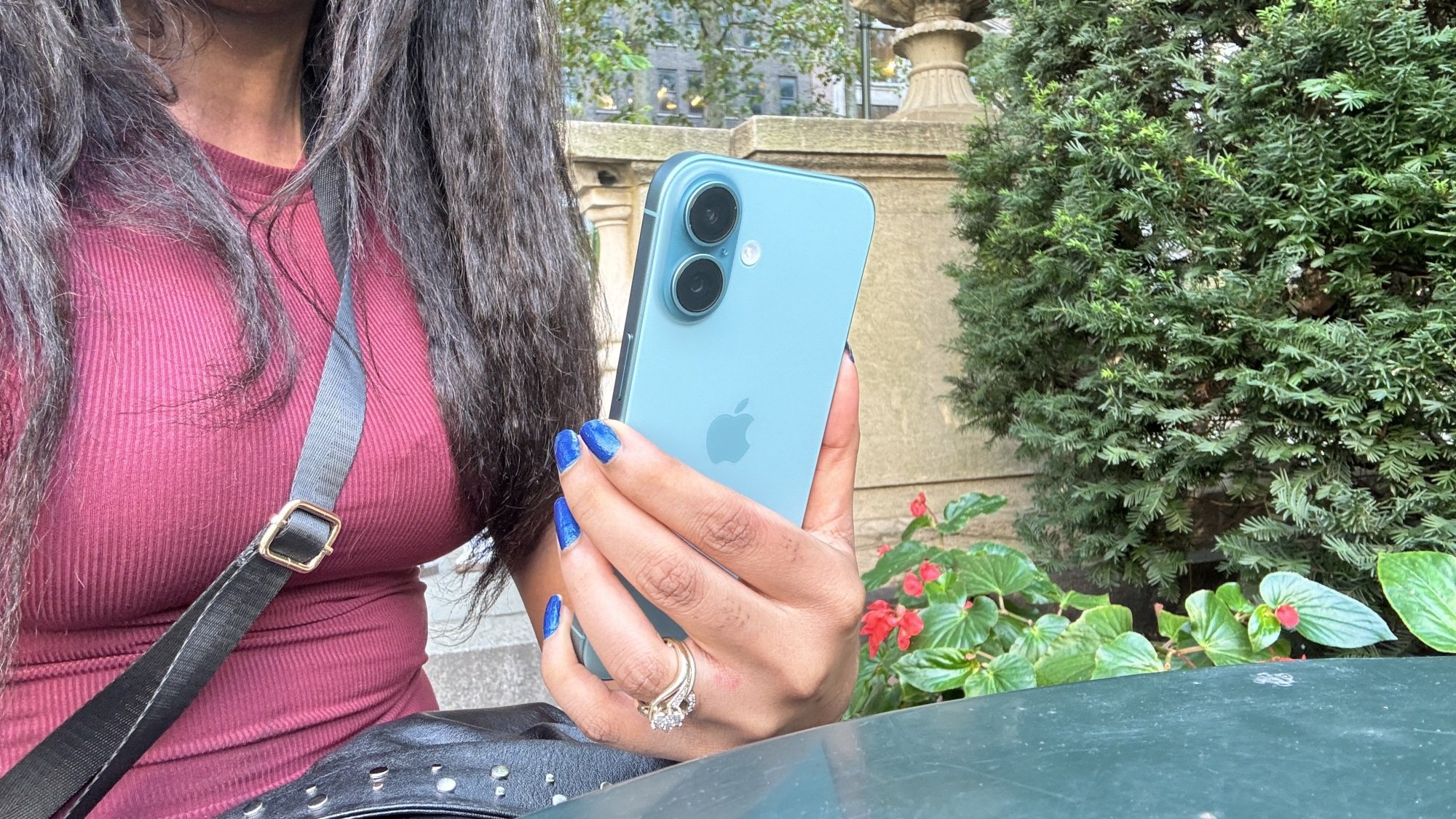 Woman holding iPhone 16 at a park