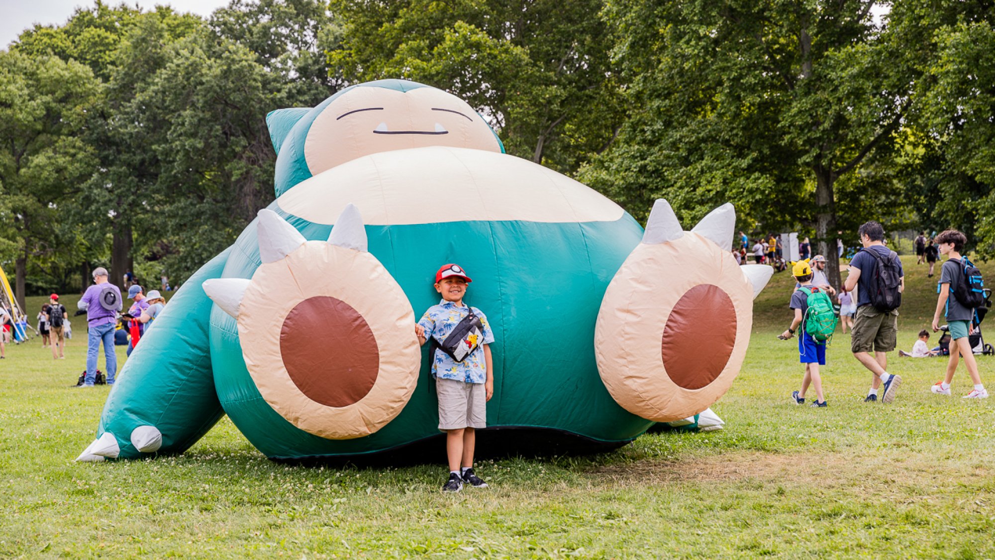 A little boy stands on front of a large Snorlax.