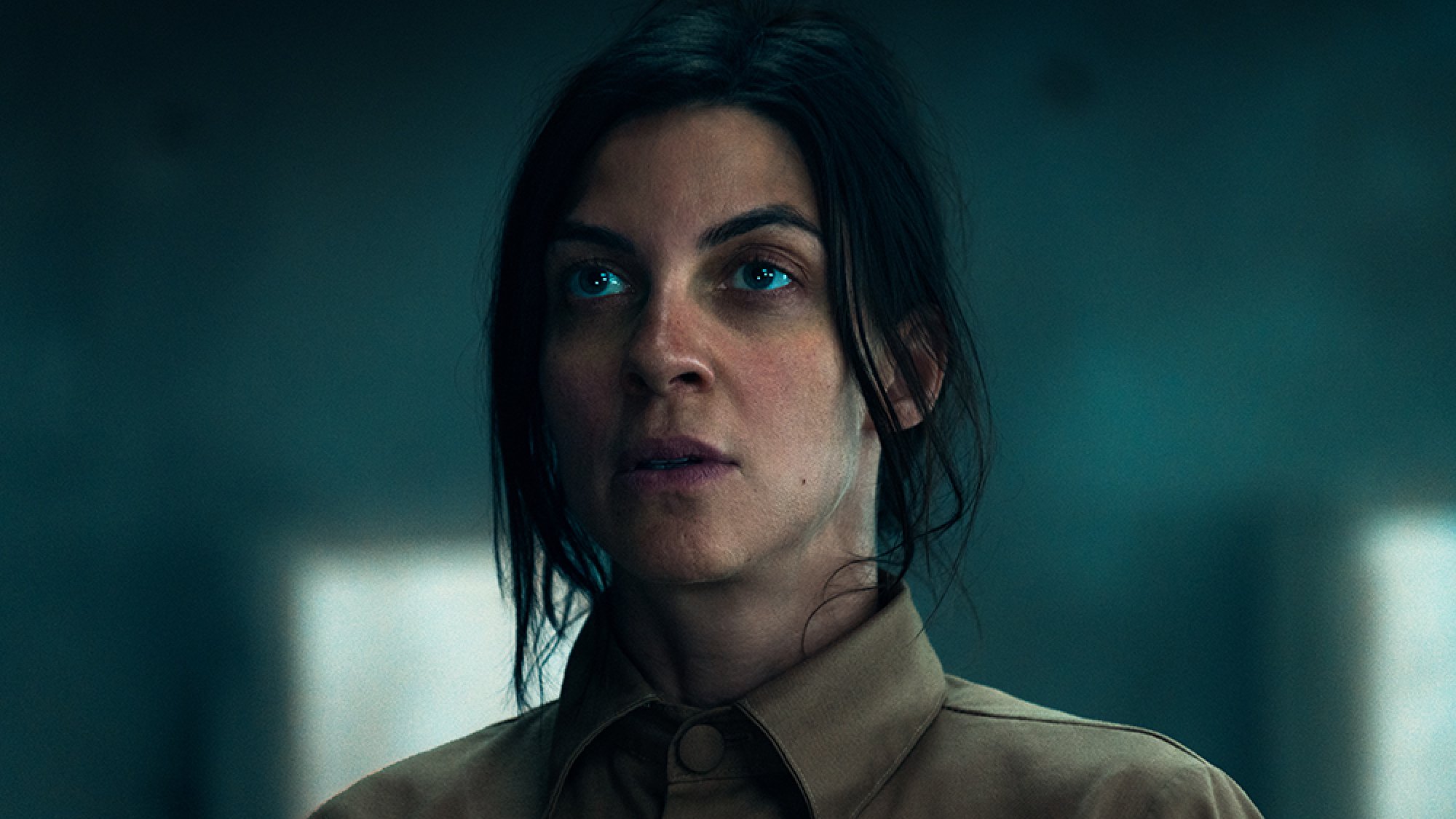 A close-up of a woman standing in a concrete room.