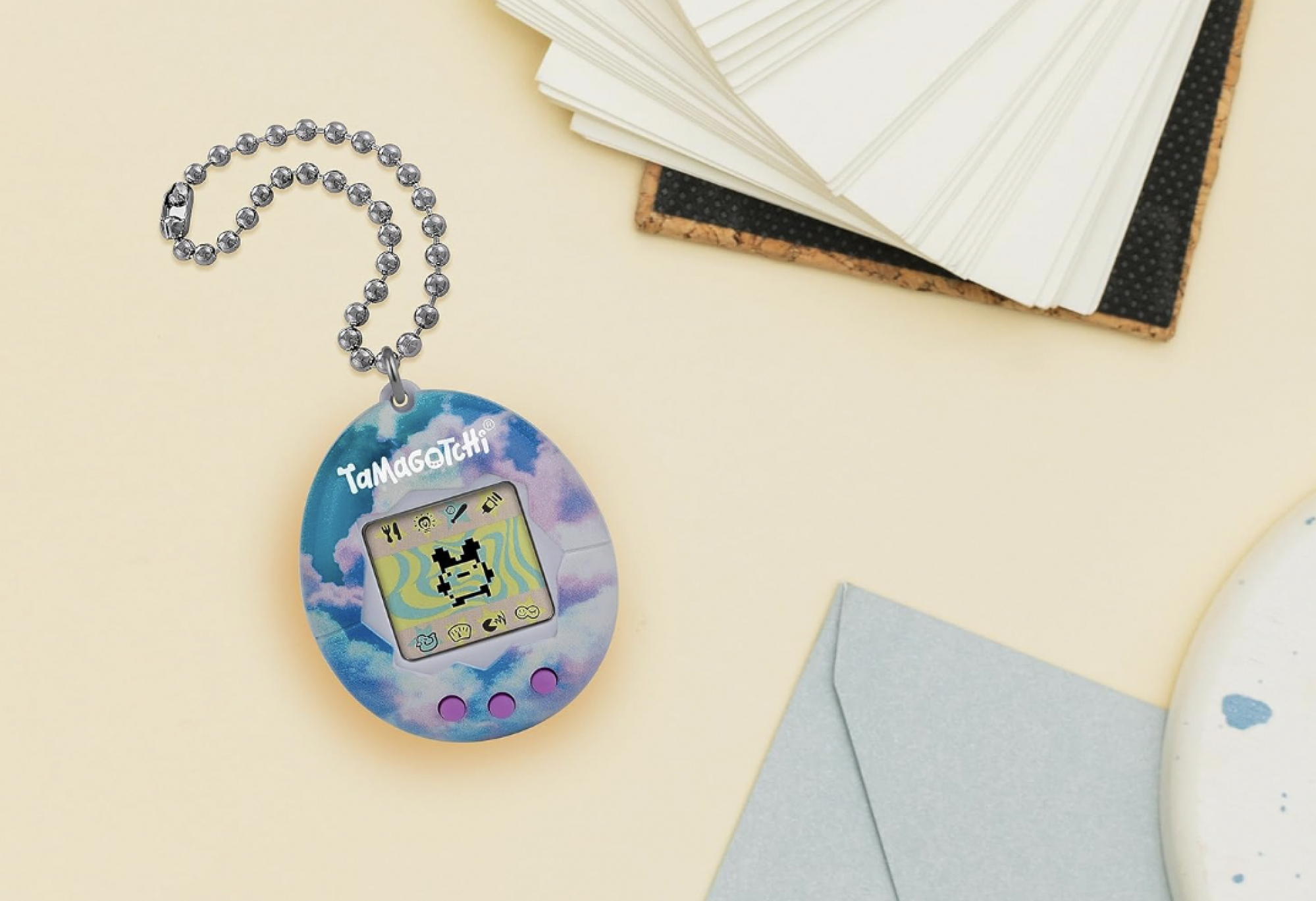 tamagotchi on table next to notebook