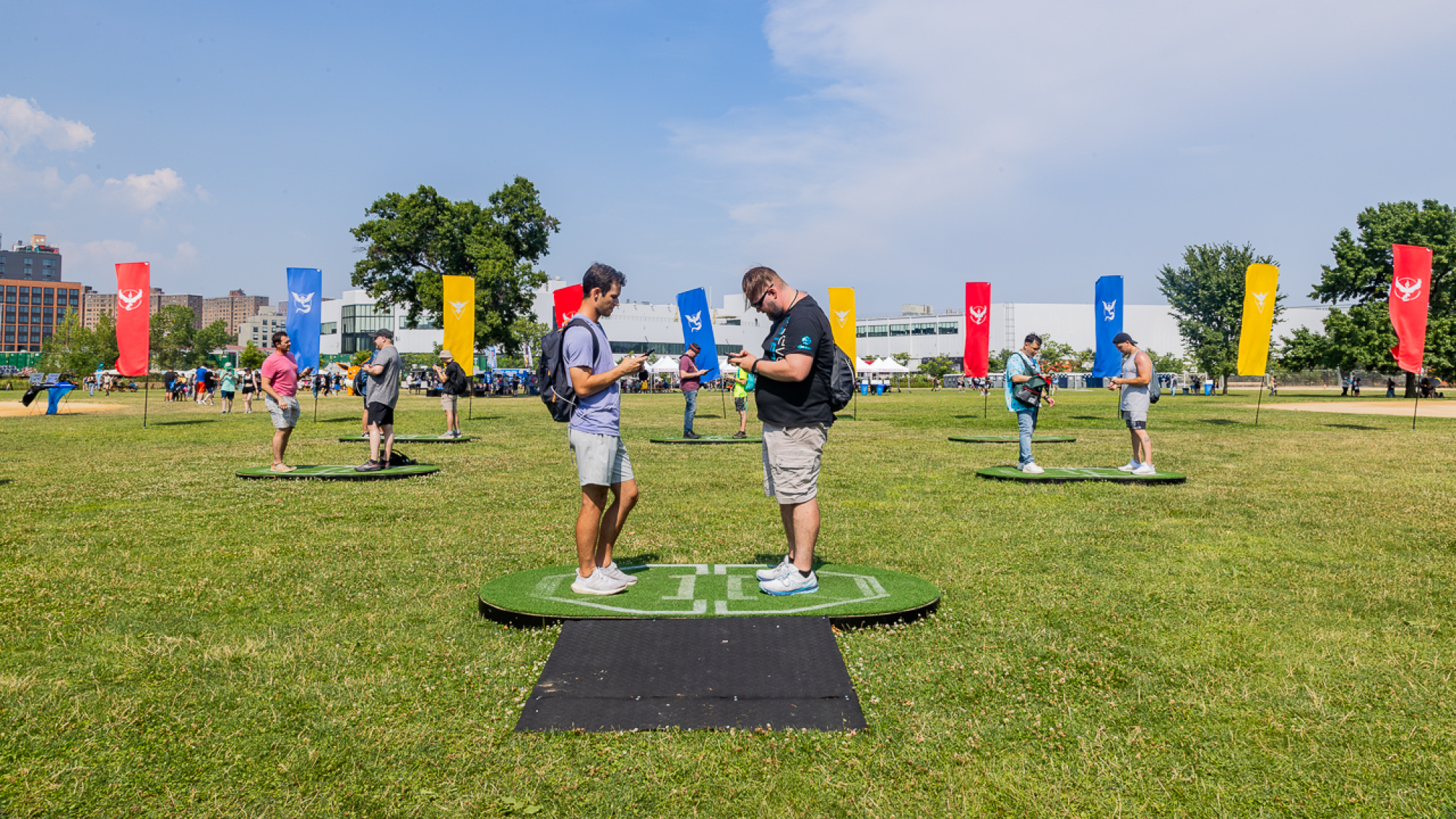 Two players stand across from each other on a lawn, battling each other on the Pokemon GO app.