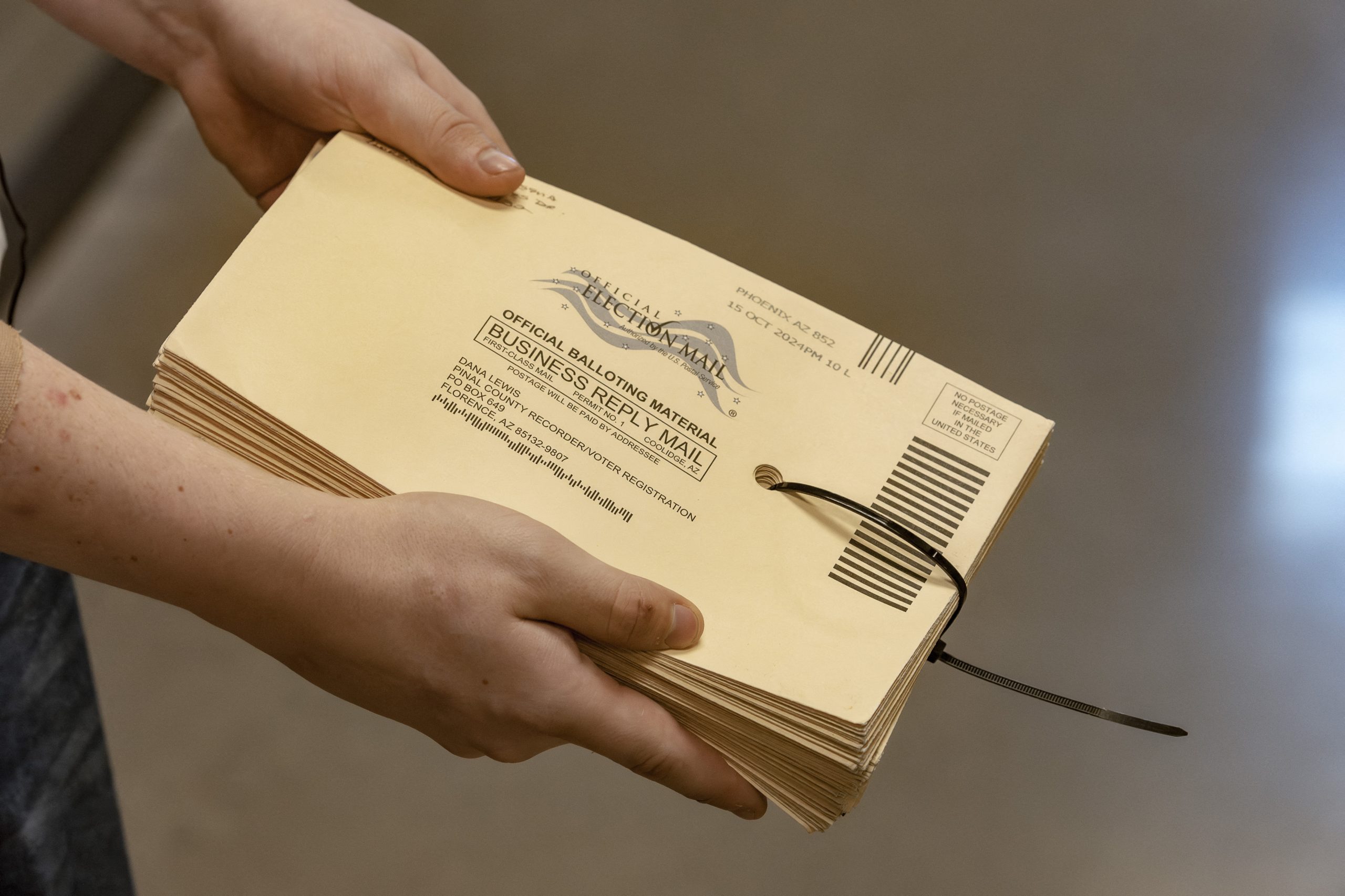 A poll worker holds a stack of ballot envelopes. 