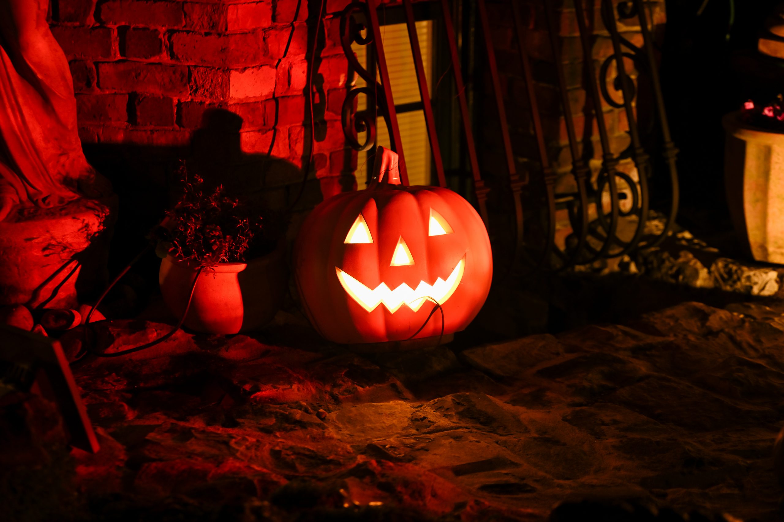 A glowing carved pumpkin sits against a brick wall in the dim light.