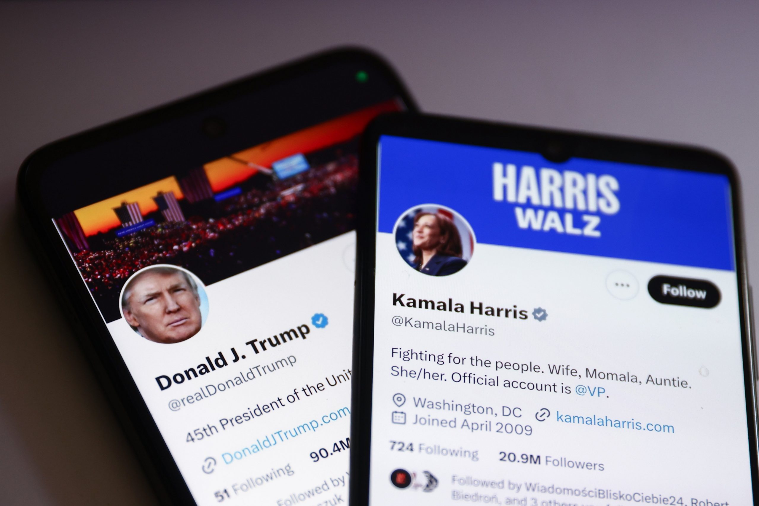 Two phones display the X/Twitter accounts of presidential candidates Donald Trump and Kamala Harris.