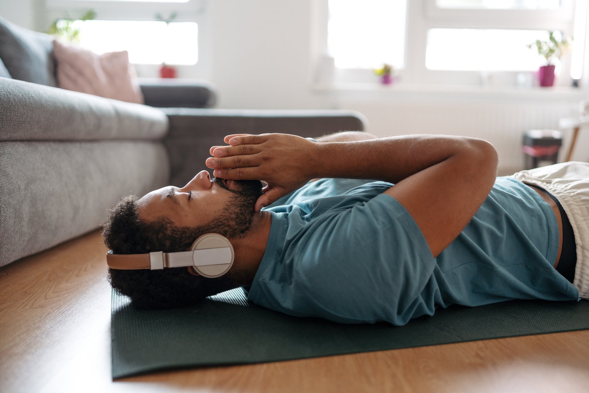 A man laying on the floor in a relaxed pose listening to headphones. 