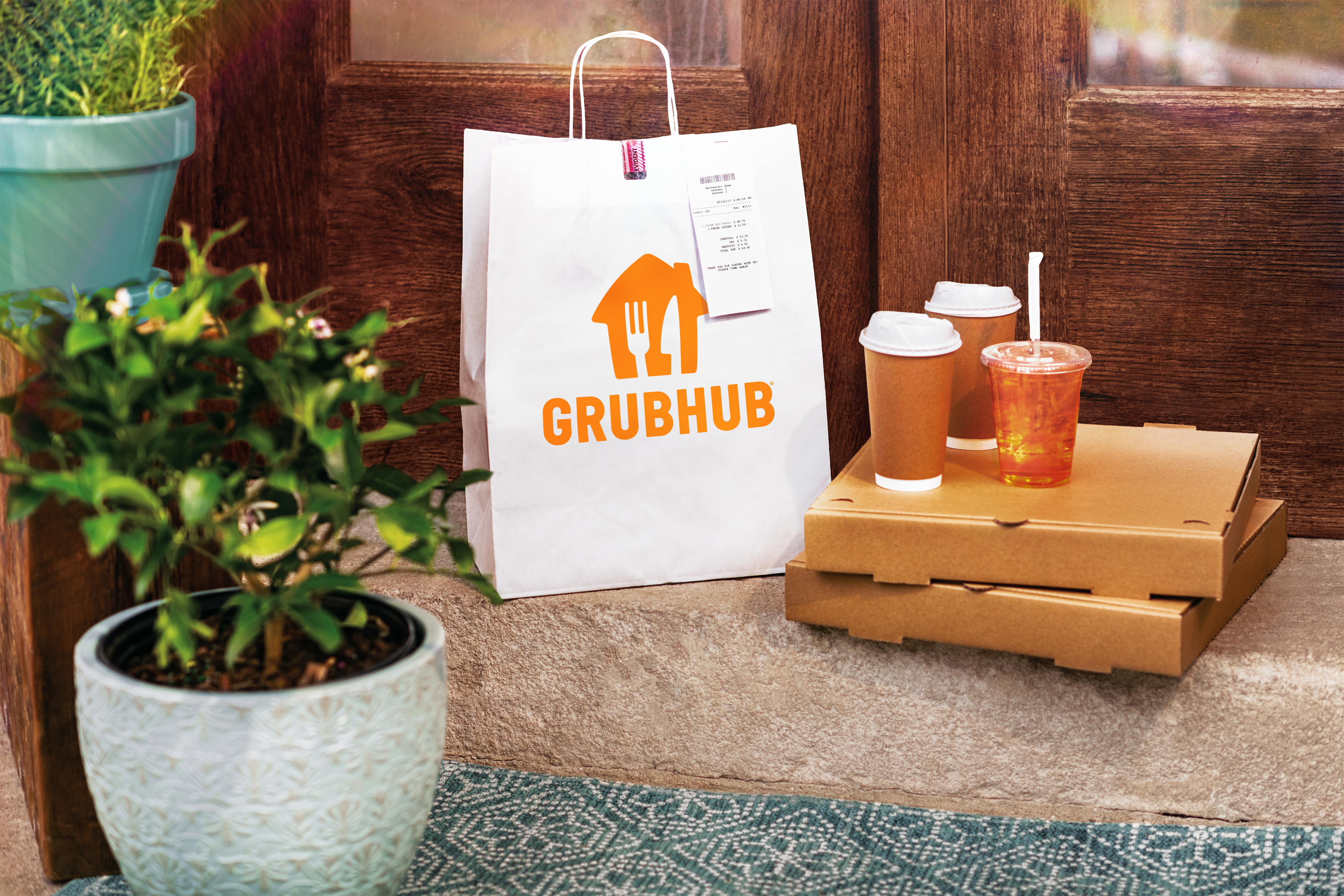 a grubhub bag on a bench with delivery boxes and drinks