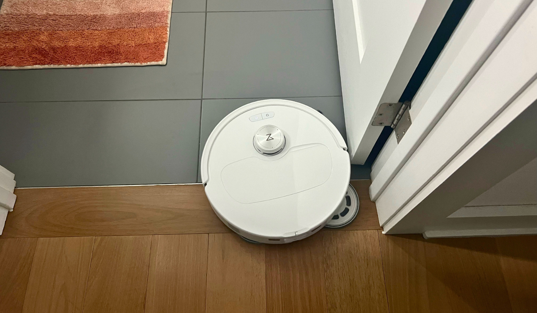 Roborock Qrevo Master robot vacuum cleaning tile and hardwood floor with rug and door in peripherals