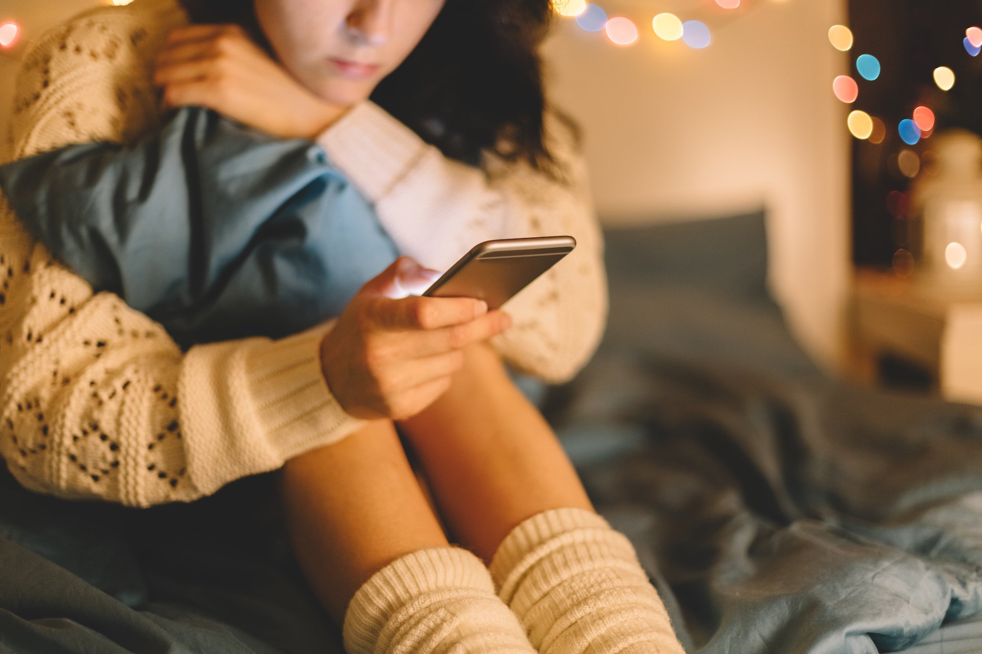 Girl looks at phone in a seated position. 