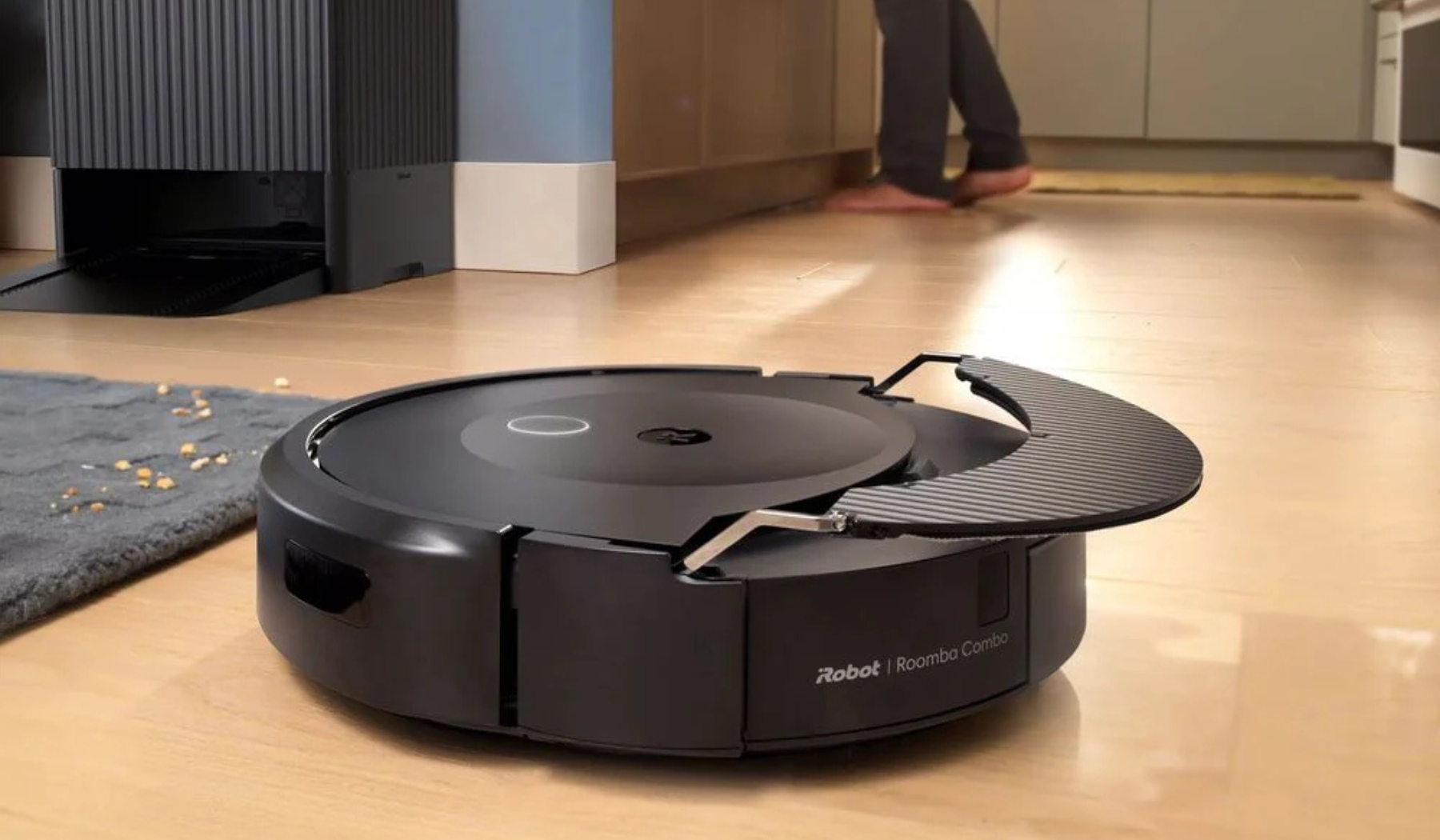 Roomba Combo 10 Max robot vacuum mopping hardwood floor with AutoWash dock in background