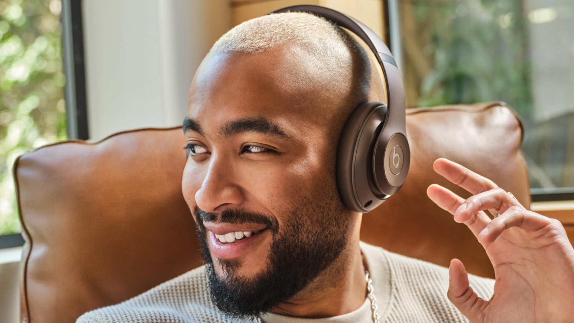 A person sitting in a chair wearing Beats Studio Pro headphones