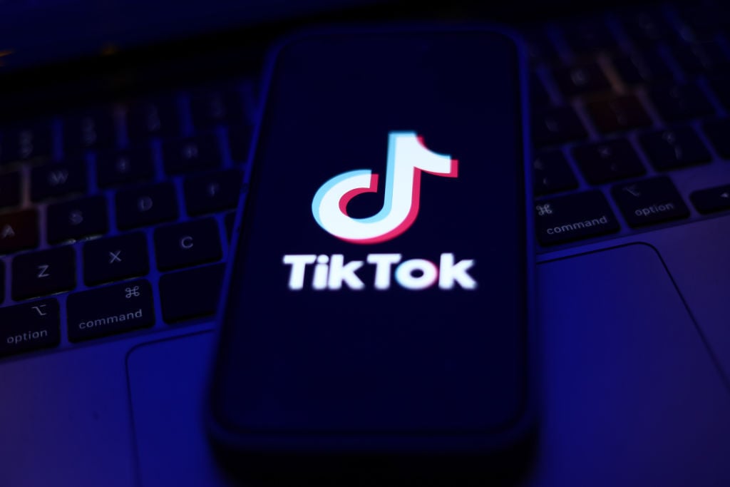 TikTok logo displayed on a phone screen and a laptop keyboard 