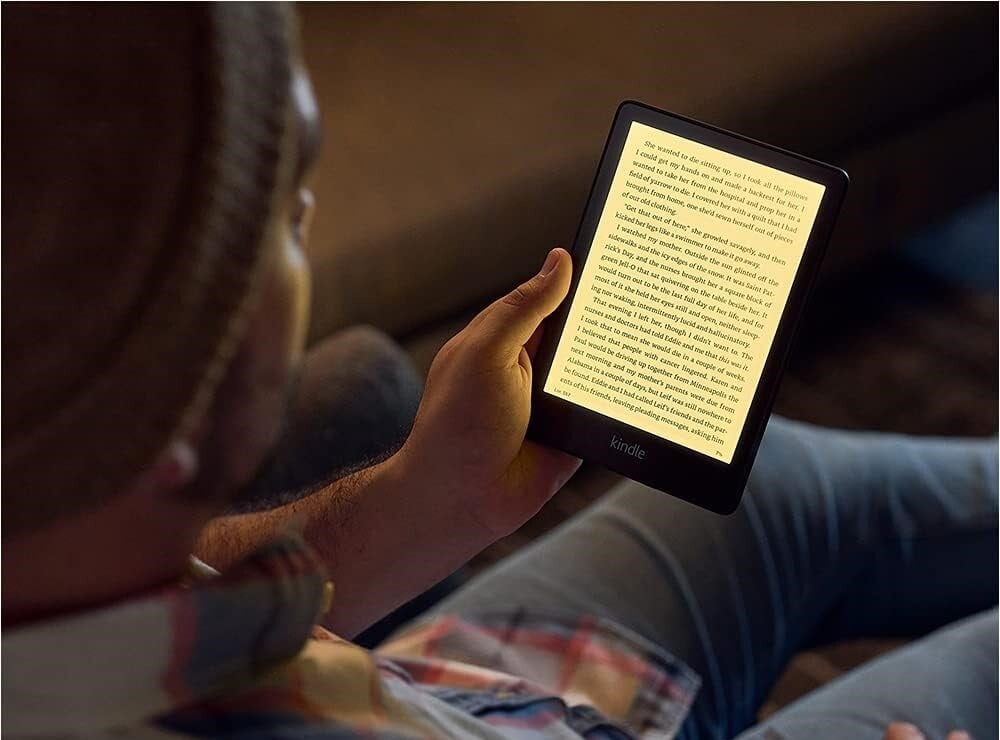 a person reads the kindle paperwhite in a dimly lit room