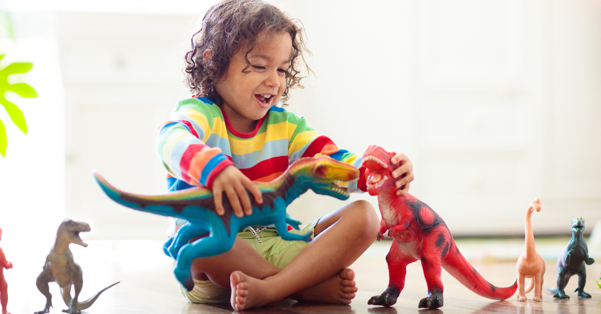 small child laughing and playing with dinosaur toys 