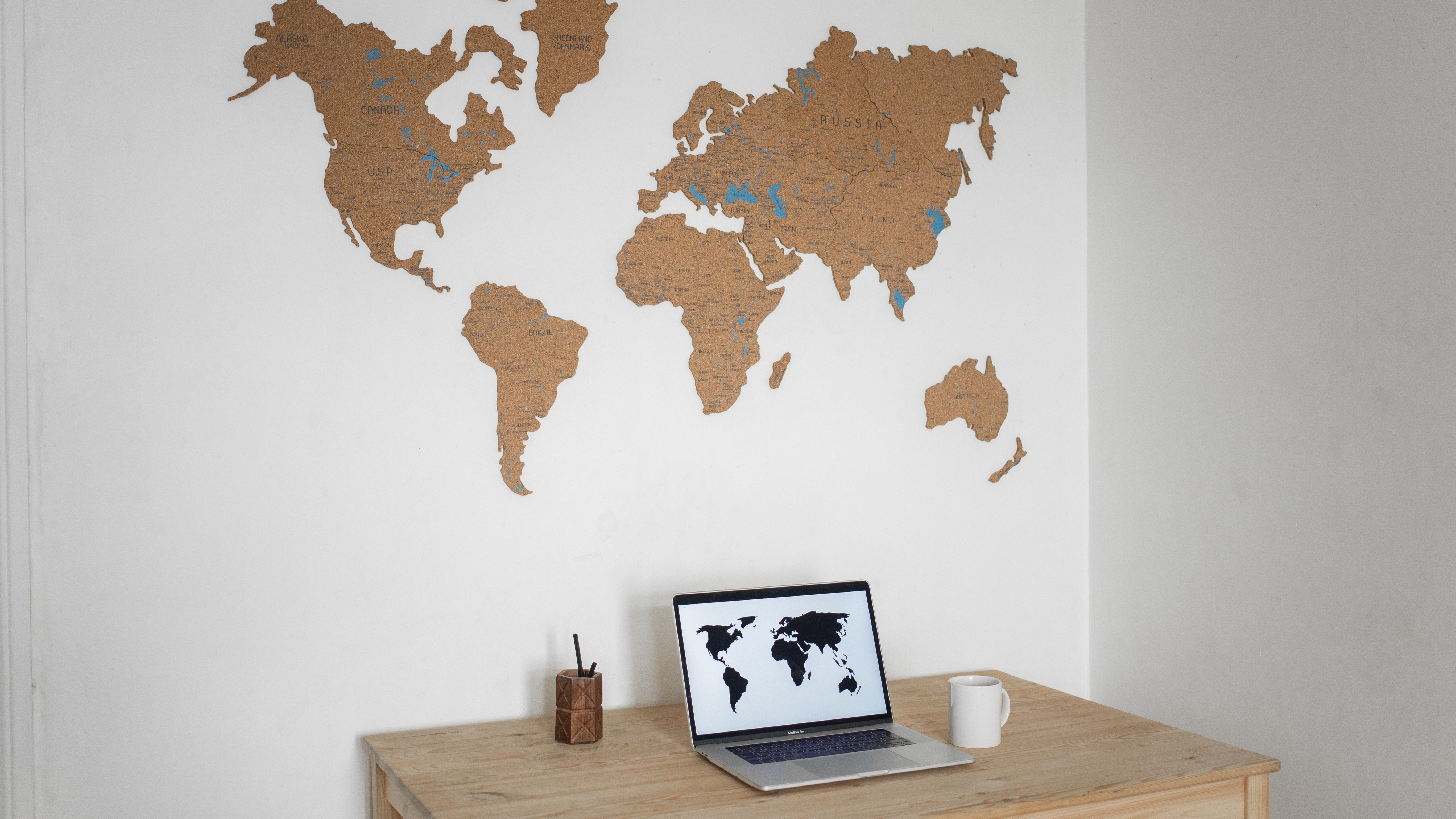 Laptop on table with map on wall