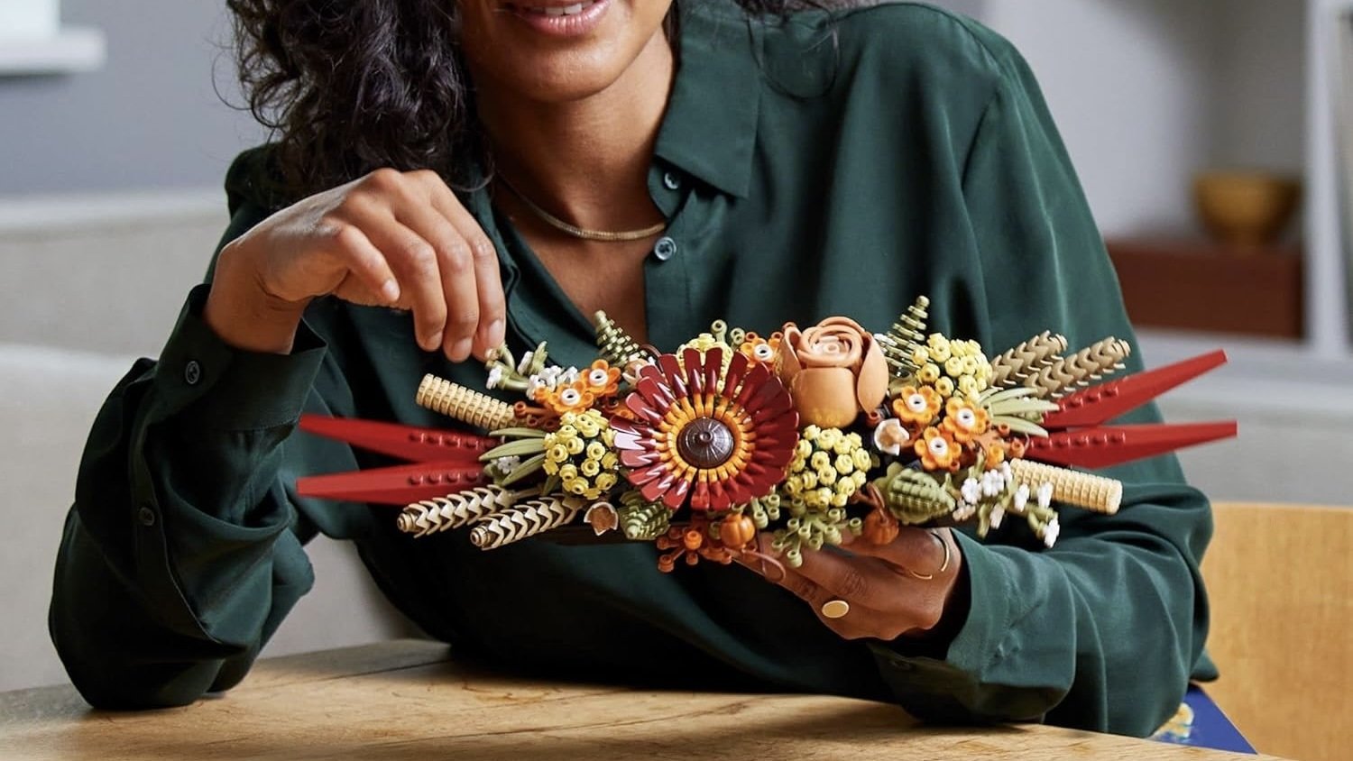 person sitting at table holding completed lego icons dried flower centerpiece