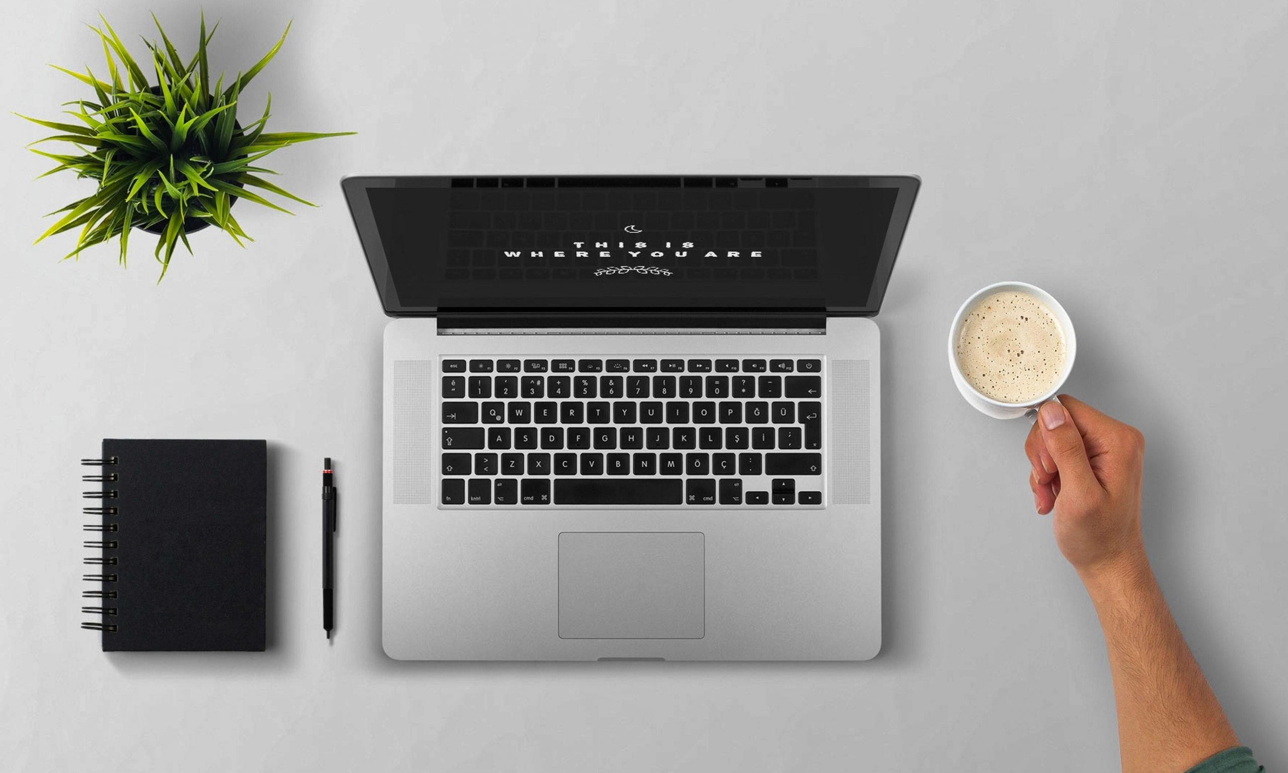 A laptop and hand with a cup of coffee